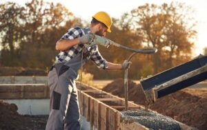 Concrete on the foundation of the house. Worker is on the construction site at daytime